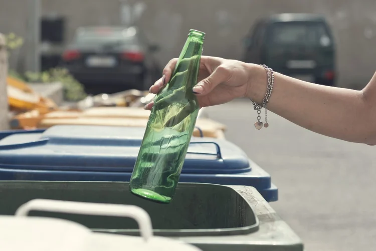 Close up hand throwing empty Glass bottle into the trash (Getty Images/Getty Images)