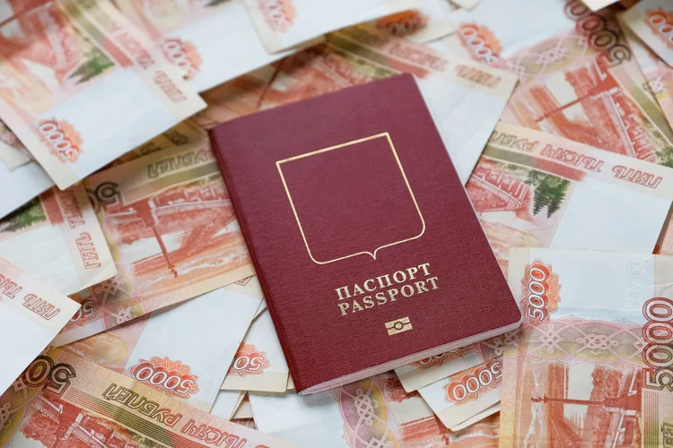 Cash five thousand Russian rubles in bills, on a white background or table. A bundle of banknotes, a Russian passport. The concept of travel and vacation abroad. Purchase of a ticket for an airplane flight. (Getty Images/Getty Images)