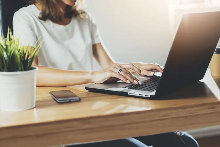 Cropped image of professional businesswoman working at her office via laptop, young female manager using portable computer device while sitting at modern loft, flare light, work process concept (Shutterstock/Shutterstock)