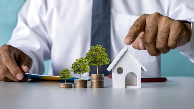 Trees grow on piles of coins and home models simulate mortgage and real estate loan ideas. (Getty/Getty Images)