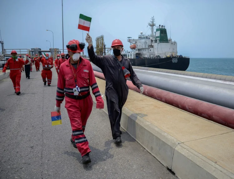 Funcionário da estatal venezuelana PDVSA agita bandeira iraniana, em 2020: sanções contra Rússia ampliam demanda por petróleo de outros países (AFP/AFP)