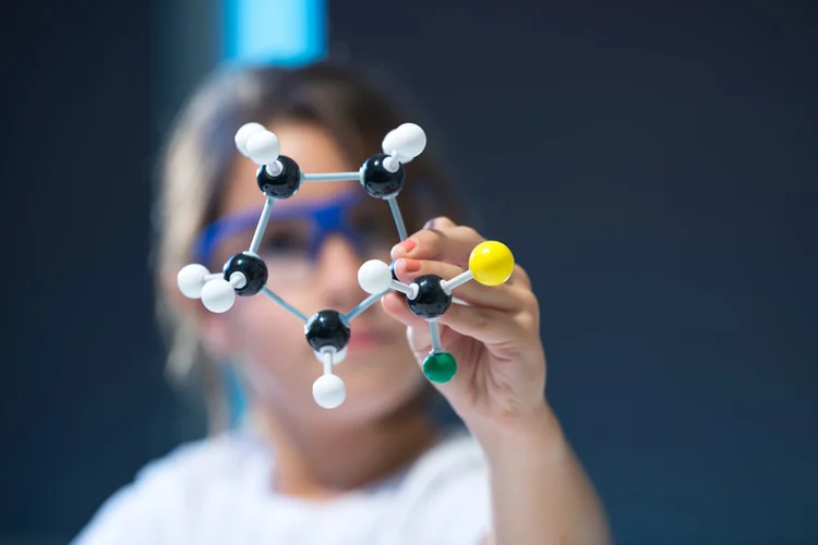 Young girl holding molecular structure in a lab. (Georgijevic/Getty Images)