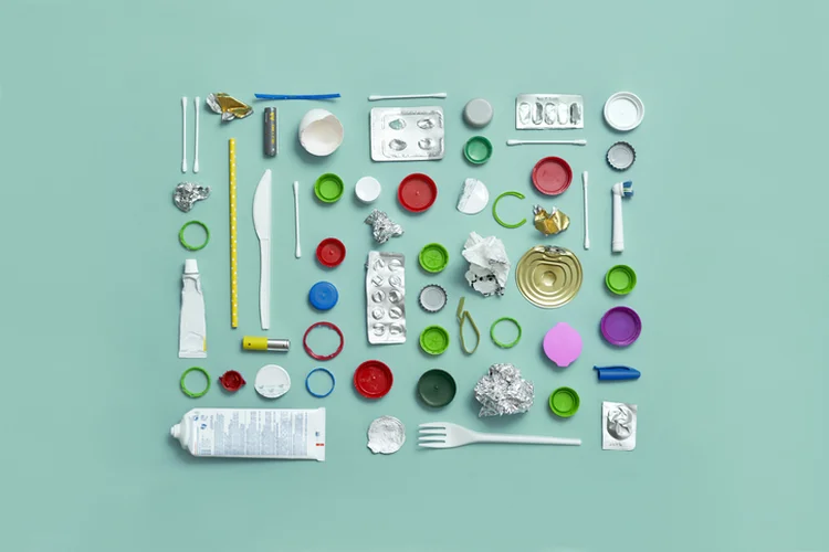 Top shot of pattern made out of recycled garbage cuch as bottle caps metal can cap, toothbrush container, pills package, paper, plastic fork... on green background. (Andriy Onufriyenko/Getty Images)