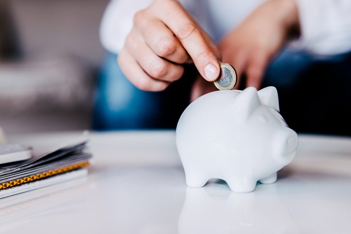 Putting a coin in a white piggy bank at home. (Getty/Getty Images)