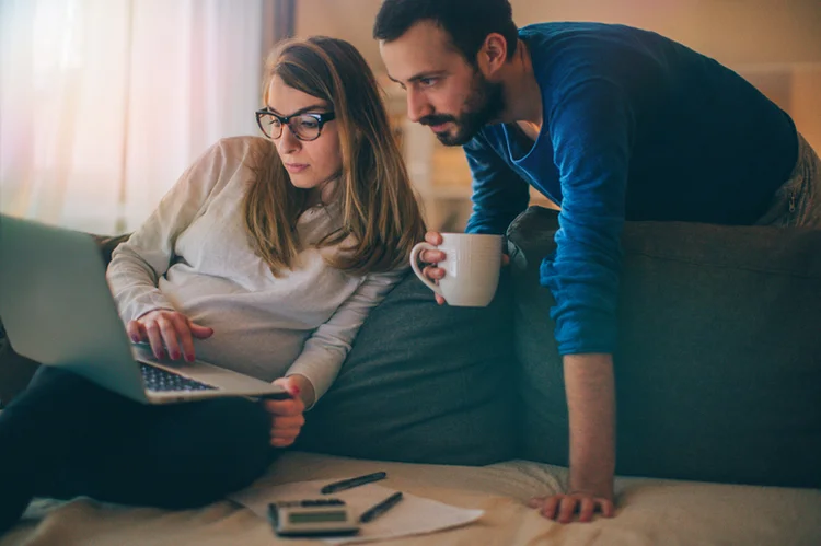 Couple sitting in their living room and checking their finances on the computer (Getty/Getty Images)