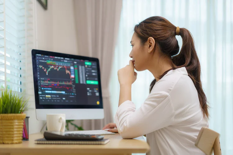 Asian woman are sitting at their desks at home trading stocks or cryptocurrency. In the living room at home. People handling various aspects of their finances from home. Depicts TradingView financial market chart. (Getty/Getty Images)