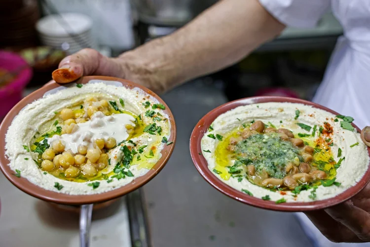 Cozinheiro se prepara para servir pratos de hummus a clientes de um restaurante na Cidade Velha de Jerusalém (AFP/AFP)