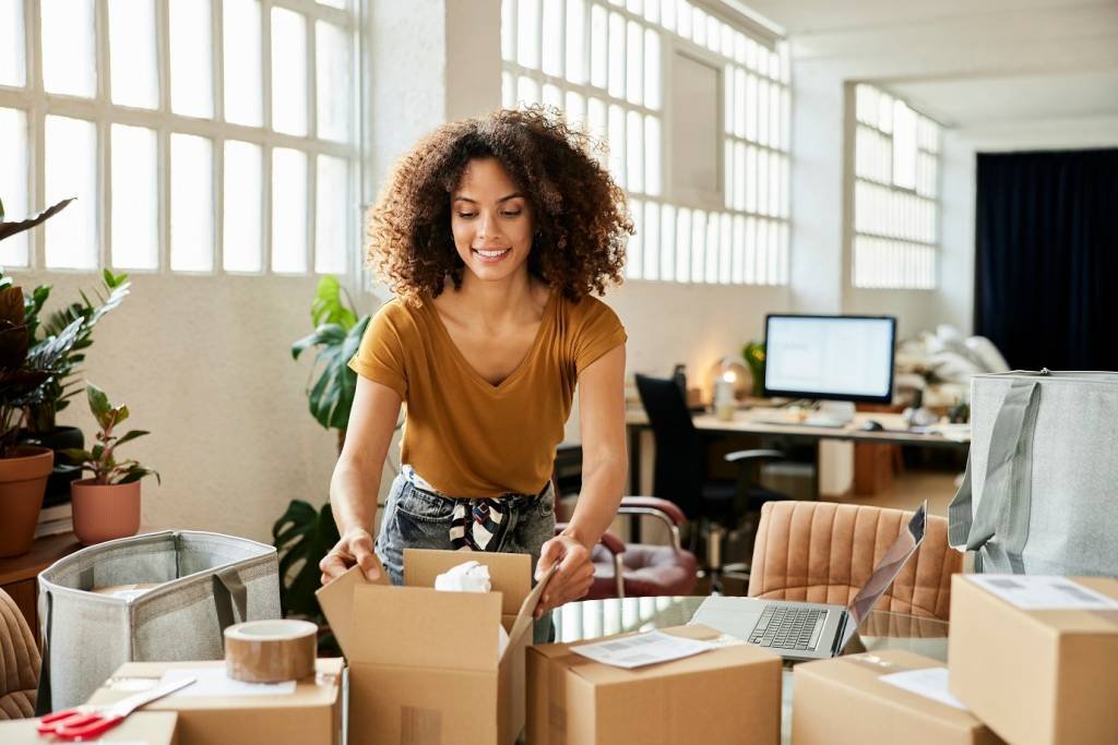 Confident businesswoman packing boxes at table. Young female entrepreneur is working at home office. She is in casuals. (Morsa Images/Getty Images)