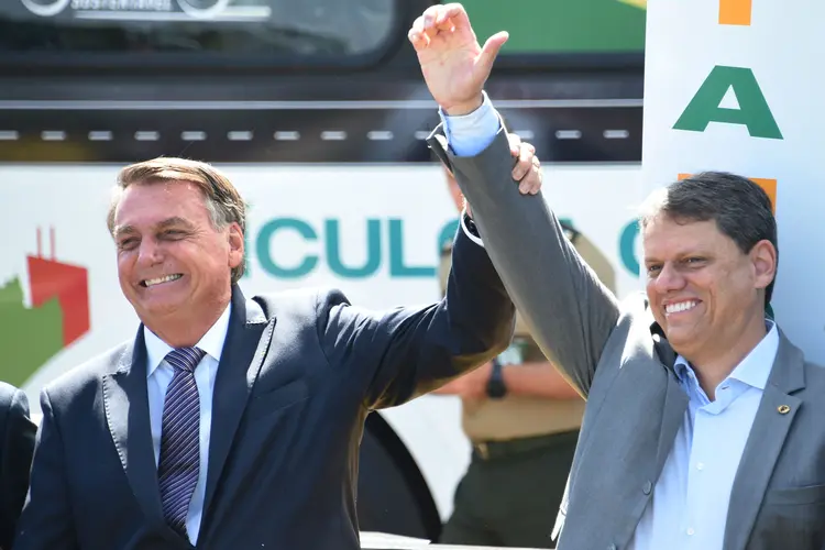 Brazilian President Jair Bolsonaro (L), on his 67th birthday, raises the arm of Infrastructure Minister Tarcisio de Freitas, during the presentation of heavy machinery powered by clean energy in the gardens of Alvorada Palace in Brasilia, on March 21, 2022. (Photo by EVARISTO SA / AFP) (Photo by EVARISTO SA/AFP via Getty Images) (EVARISTO SA/Getty Images)