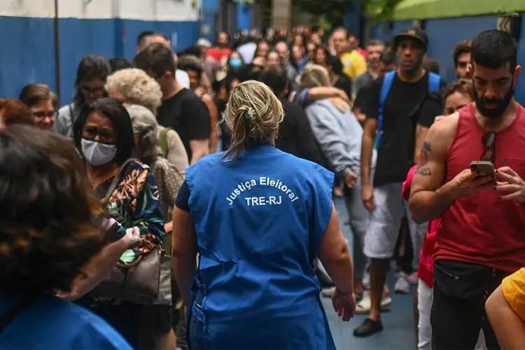 Um funcionário da Justiça Eleitoral caminha enquanto as pessoas fazem fila em uma estação de votação no Rio de Janeiro (André Borges/AFP/Getty Images)