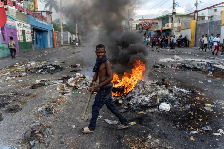 Um homem passa por uma barricada em chamas durante um protesto pedindo a renúncia do primeiro-ministro haitiano, em uma rua de Porto Príncipe, em 10 de outubro de 2022 (AFP/Divulgação)