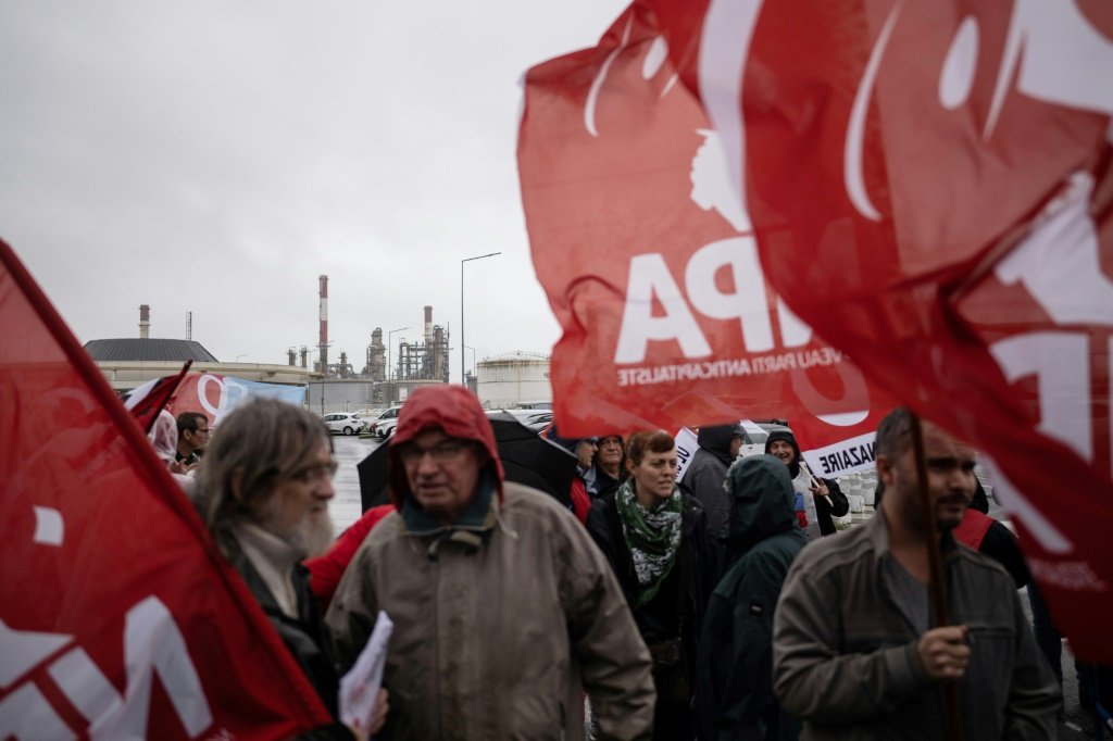 Sindicalistas e funcionários em greve se reúnem do lado de fora da refinaria TotalEnergies, em Donges, oeste da França (AFP/Divulgação)