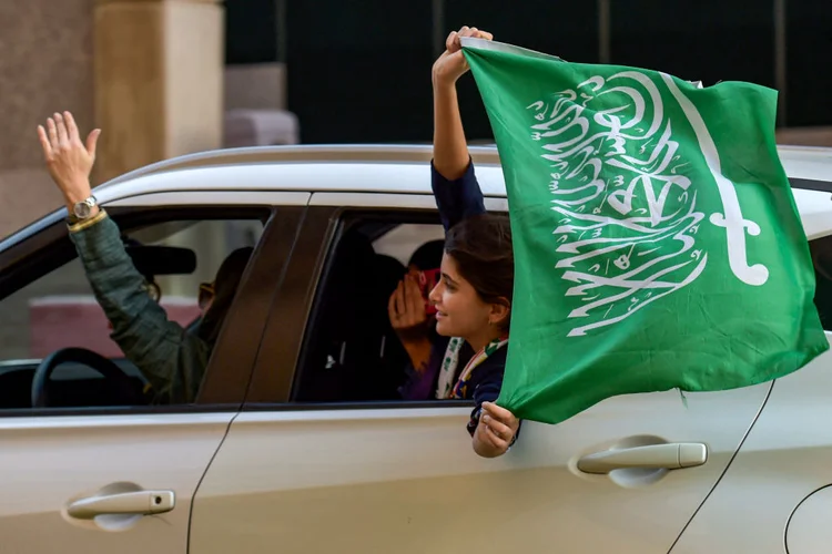 Um torcedor de futebol saudita agita a bandeira de seu país da janela de um carro em Riad em meio às comemorações da vitória da Arábia Saudita sobre a Argentina na Copa do Mundo do Catar 2022 (AMER HILABI/AFP/AFP Photo)