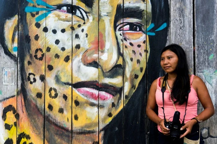Índigena matis posa ao lado de mural na Amazônia colombiana (AFP/AFP)