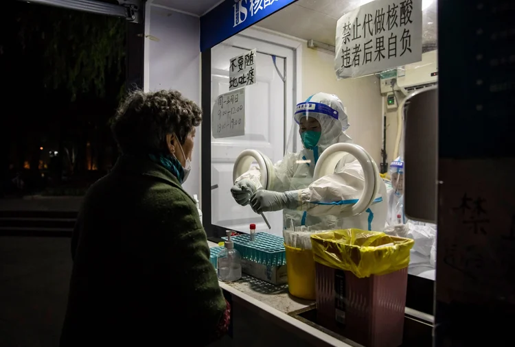 A worker in protective gear swabs a resident at a Covid-19 testing facility in Shanghai, China, on Friday, Dec. 2, 2022. China's top leaders will likely signal a more pragmatic approach toward Covid controls at a key upcoming meeting while putting more focus on boosting economic growth, economists say. Photographer: Qilai Shen/Bloomberg (Qilai Shen/Bloomberg)