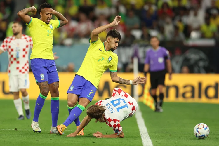 Brazil's midfielder #07 Lucas Paqueta (C) fights for the ball with Croatia's defender #19 Borna Sosa (R) next tp Brazil's defender #14 Eder Militao during the Qatar 2022 World Cup quarter-final football match between Croatia and Brazil at Education City Stadium in Al-Rayyan, west of Doha, on December 9, 2022. (Photo by Adrian DENNIS / AFP) (Photo by ADRIAN DENNIS/AFP via Getty Images) (ADRIAN DENNIS/AFP/Getty Images)