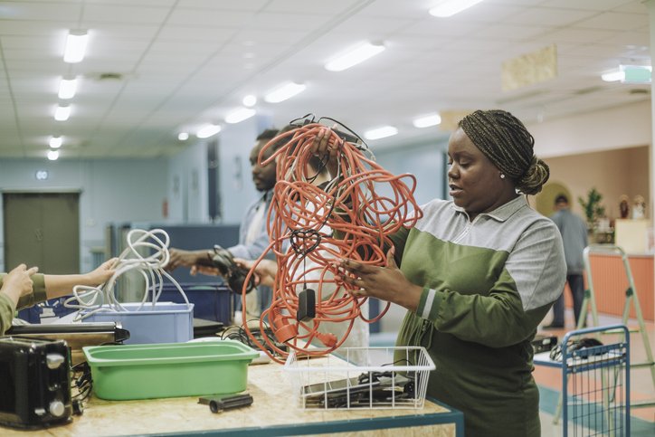 Female and male colleagues working with tangled cable wires in recycling center