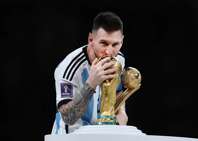 LUSAIL CITY, QATAR - DECEMBER 18: Lionel Messi of Argentina kisses the FIFA World Cup Qatar 2022 Winners' Trophy while holding the adidas Golden Boot award after the FIFA World Cup Qatar 2022 Final match between Argentina and France at Lusail Stadium on December 18, 2022 in Lusail City, Qatar. (Photo by Maja Hitij - FIFA/FIFA via Getty Images) (Maja Hitij - FIFA/FIFA/Getty Images)
