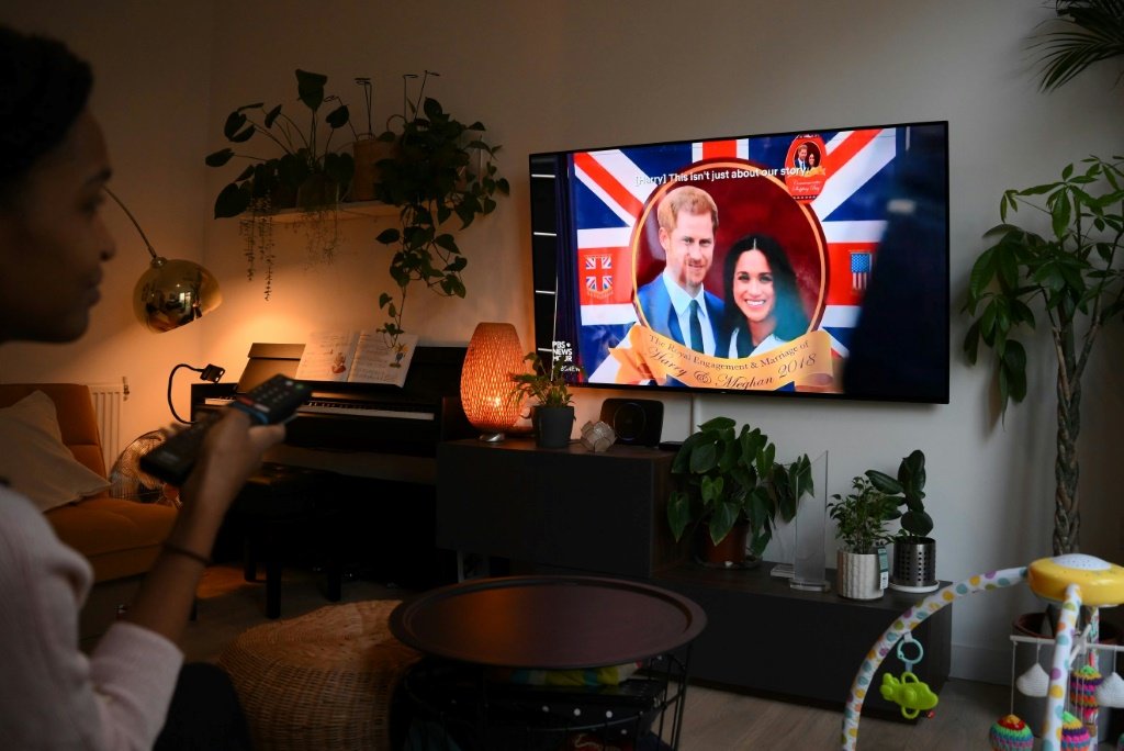 Uma mulher posa enquanto assiste a um episódio da recém-lançada série documental da Netflix "Harry & Meghan" (AFP/AFP)
