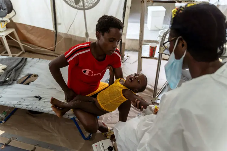 Mulher segura menino com sintomas de cólera enquanto ele recebe tratamento em uma clínica da ONG Médicos Sem Fronteiras na comunidade de Cité Soleil em Porto Príncipe, Haiti, em 7 de outubro de 2022 (Robin MILLARD/AFP Photo)