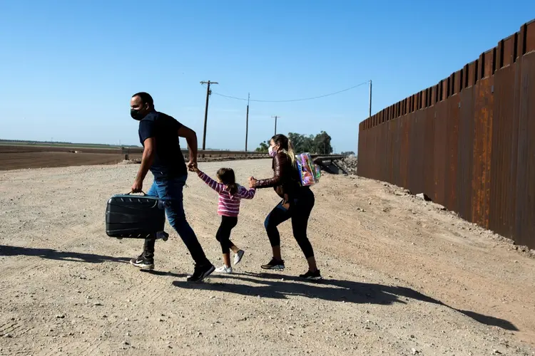 Família de migrantes cubanos passa pelo muro que separa o México dos Estados Unidos para se entregar às autoridades em Yuma, Arizona. (AFP/AFP)
