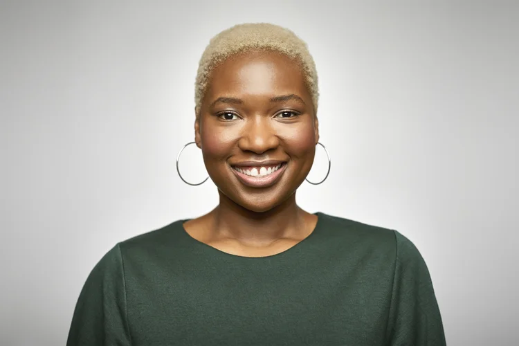 Portrait of young businesswoman smiling. Close-up of confident female professional is having short blond hair. She is wearing green top against white background."n (Getty Images/Getty Images)