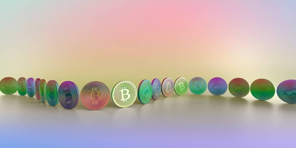 A pastel toned, multi-coloured image of two toned generic coin with Bitcoin symbol, arranged in a row, or chain along a curve against a multi coloured background. Denotes concept of block-chain and crypto-currency. With lots of copy space. (Getty Images/Reprodução)
