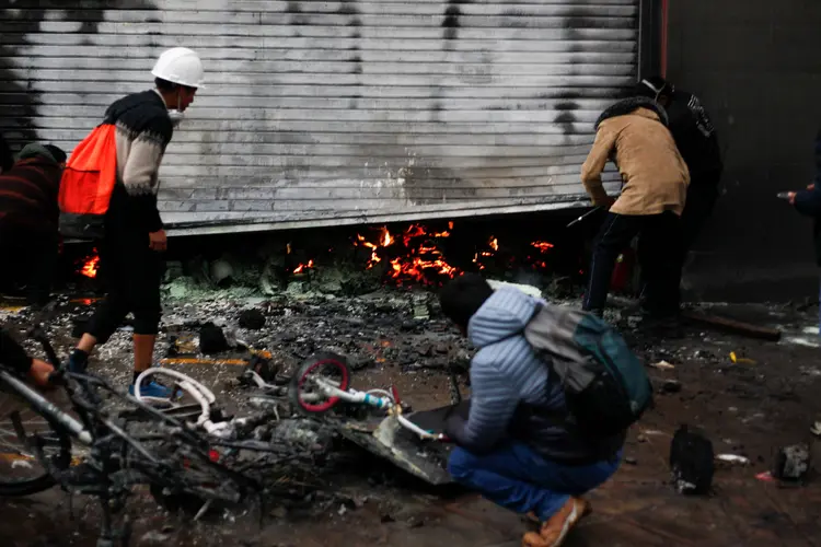 Supermarket workers inspect the fire damage after clashes erupted between riot police and anti-government protesters in Puno, Peru, on January 9, 2023. - At least 12 people died Monday in Peru as anti-government protesters trying to overrun an airport clashed with security forces, officials said. The violence took place in the southeastern city of Juliaca, in the Puno region, an official in the local ombudsman's office told AFP. (Photo by Juan Carlos CISNEROS / AFP) (Photo by JUAN CARLOS CISNEROS/AFP via Getty Images) (JUAN CARLOS CISNEROS/Getty Images)