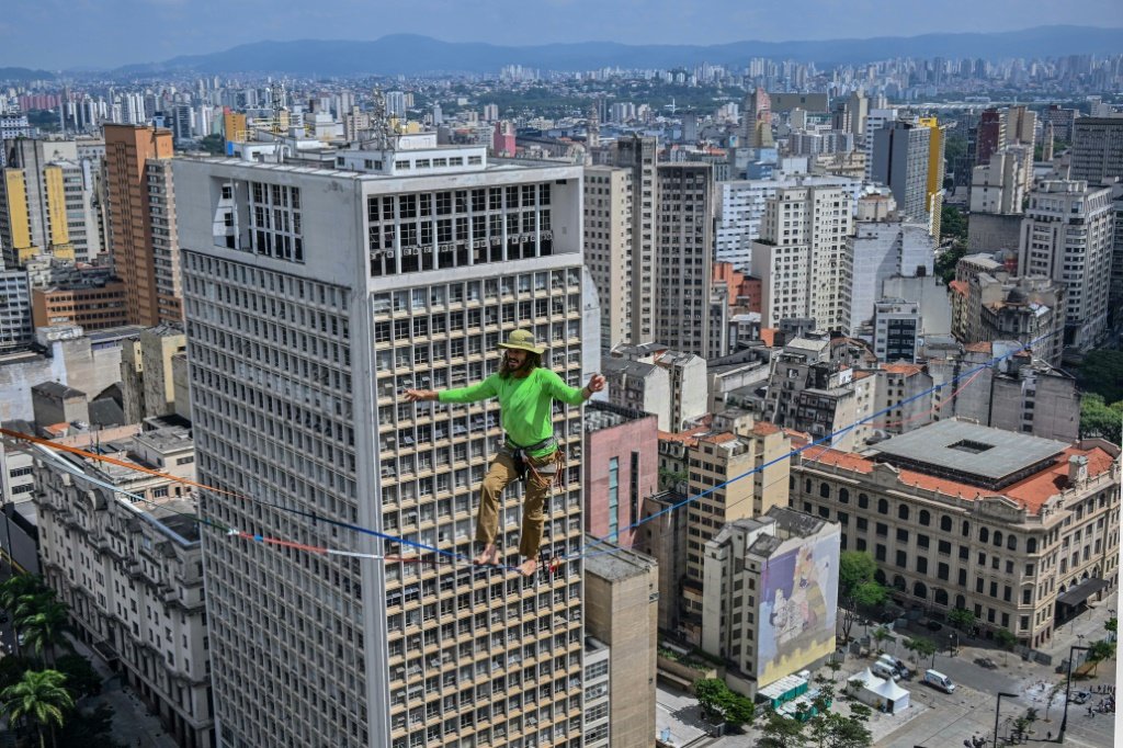 O highliner brasileiro Rafael Bridi se apresenta em um slackline a 114 metros de altitude e 510 metros de extensão, cruzando todo o Vale do Anhangabaú, como parte do 469° aniversário da cidade de São Paulo. (AFP/AFP)