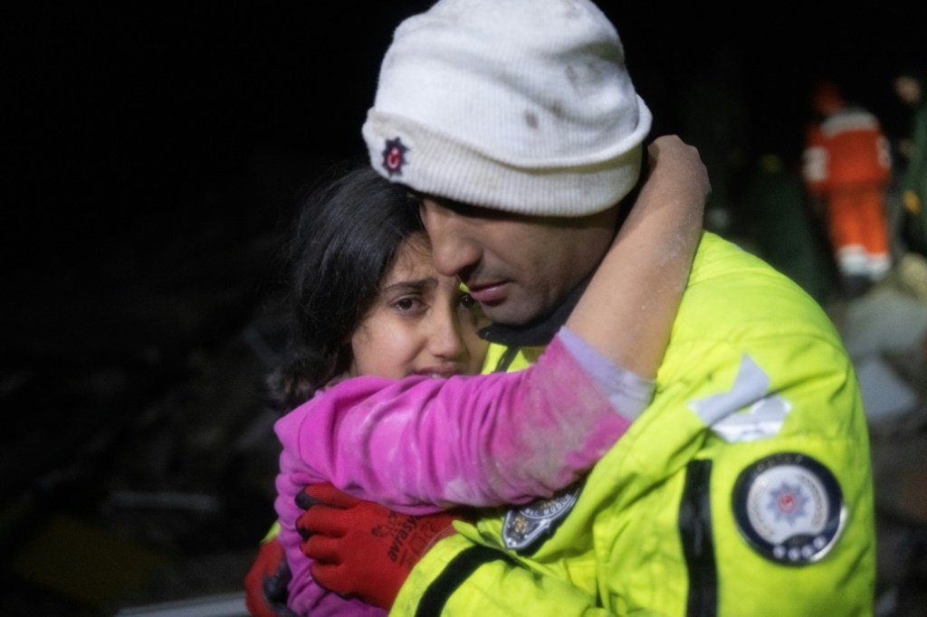 Menina recebe ajuda de policial: equipes de resgate têm de lutar contra o tempo e o frio (KADIR DEMIR, BULENT KILIC/AFP)