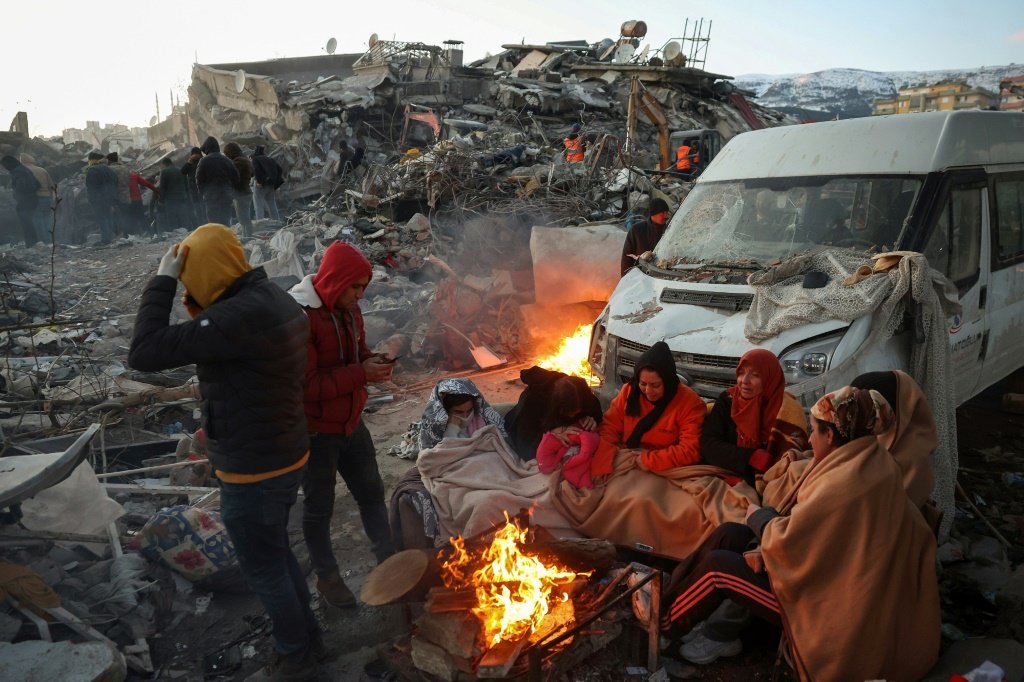 Terremoto na Turquia: sobreviventes do terremoto perto de fogueira em Kahramanmaras (KADIR DEMIR, COM OMAR HAJ KADOUR EM HAREM (SÍRIA)/AFP)