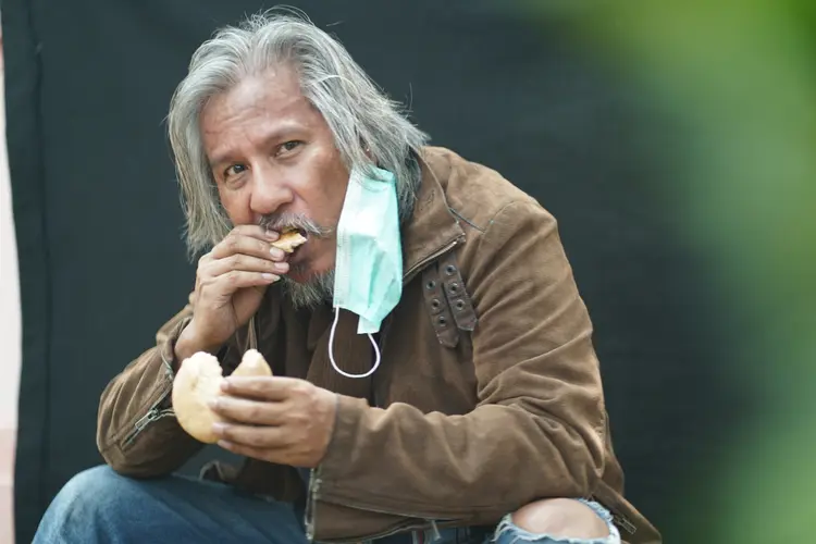 Close-up homeless man portrait eating bread on walking street. (Getty Images/Getty Images)
