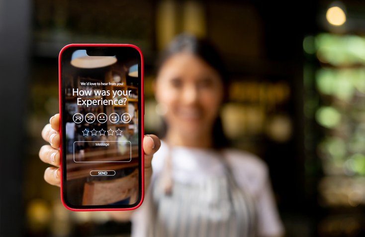 Waitress displaying an app to rate your experience at a restaurant â food and drink industry concepts (Hispanolistic/Getty Images)