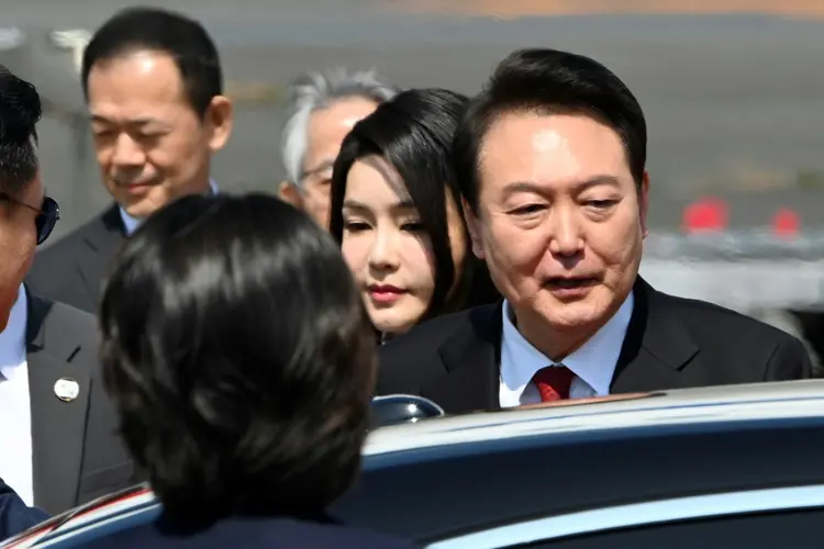 O presidente sul-coreano Yoon Suk Yeol (D) e a esposa Kim Keon Hee (C) no aeroporto de Tóquio em 16 de março de 2023 (AFP/Reprodução)