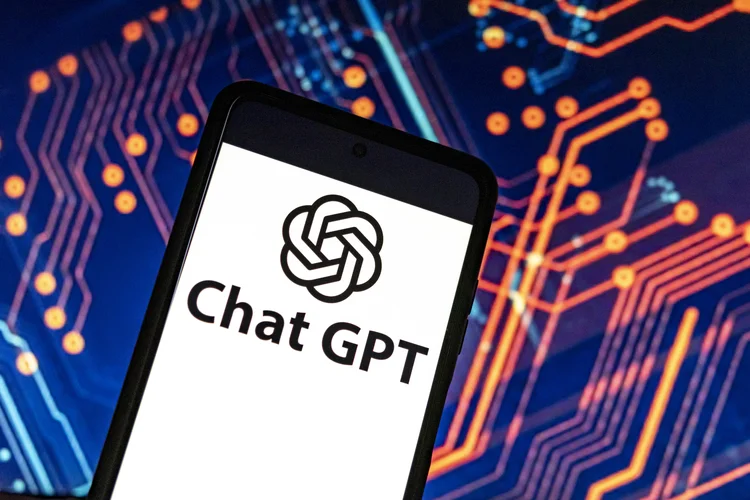 Photo illustration showing ChatGPT and OpenAI research laboratory logo and inscription at a mobile phone smartphone screen with a blurry background. Open AI is an app using artificial intelligence technology. Italy is the first European country to ban and block the robot Chat GPT application and website. ChatGPT is an artificial-intelligence (AI) chatbot developed by OpenAI and launched in November 2022 using reinforcement learning techniques both from machine and human feedback. Amsterdam, the Netherlands on April 1, 2023 (Photo by Nicolas Economou/NurPhoto via Getty Images) (Nicolas Economou/NurPhoto/Getty Images)