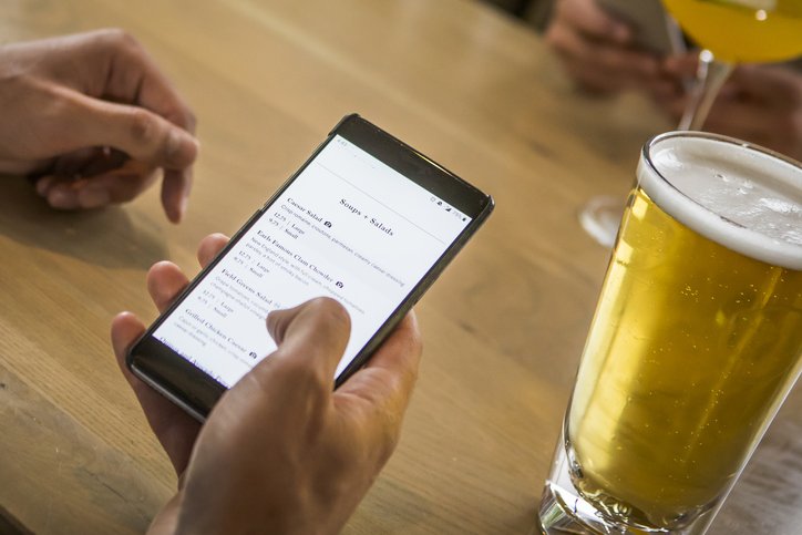 Checking menu on smart phone at the pub. (VisualCommunications/Getty Images)