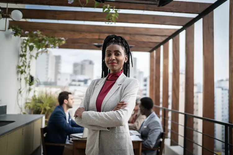 Portrait of a confident businesswoman outdoors - team meeting on the background (Getty Images/Reprodução)
