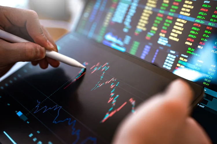 Market Analyze with Digital Monitor focus on tip of finger. (Jackyenjoyphotography/Getty Images)