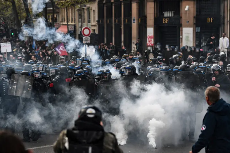 Policiais em tropa de choque em formação em meio a fumaça de bombas perto dos escritórios do banco central do Banque de France na Place de la Bastille durante confrontos com manifestantes (CHRISTOPHE ARCHAMBAULT / Colaborador/Getty Images)