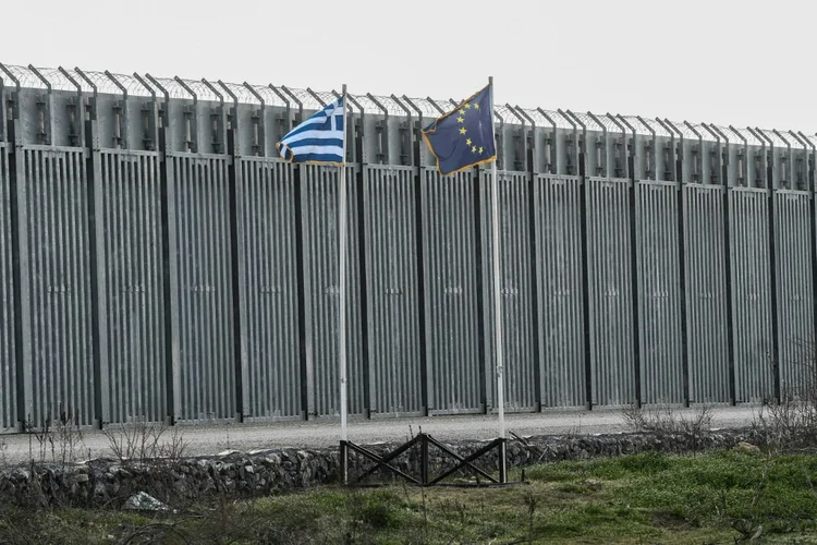 Uma bandeira grega tremula ao vento, ao lado das 12 estrelas amarelas sobre um fundo azul da bandeira europeia (AFP/AFP Photo)