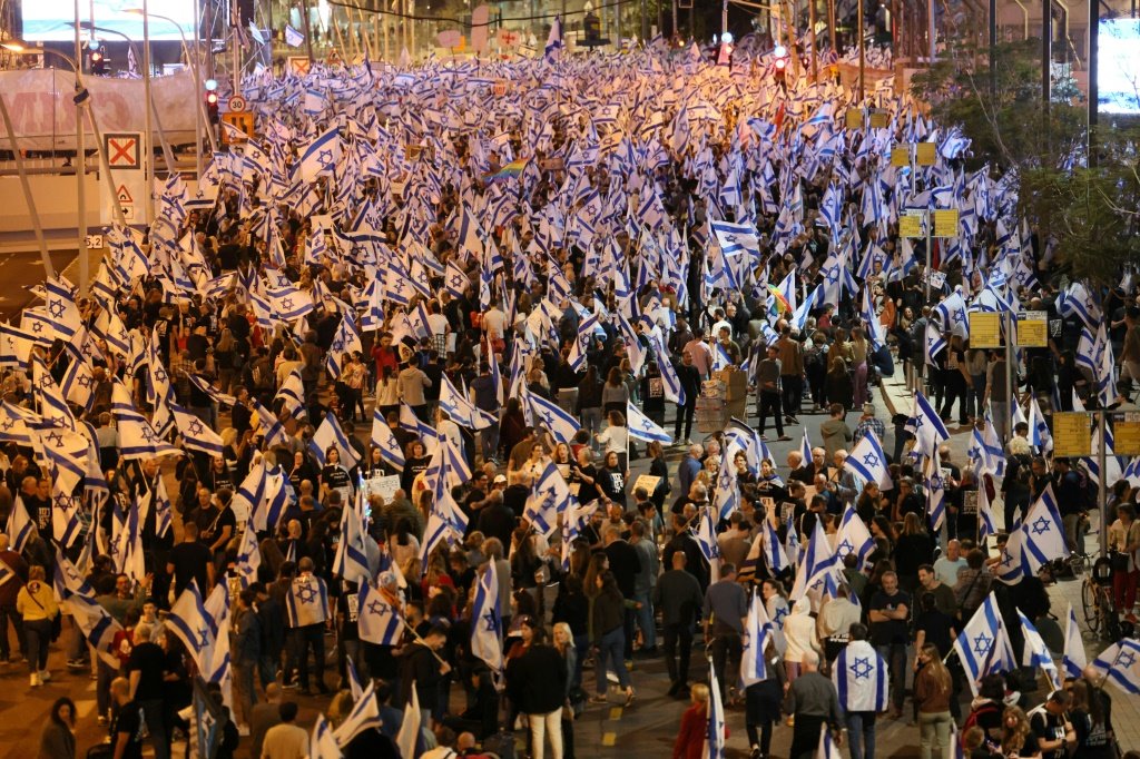 Manifestantes marcham com bandeiras de Israel em meio a manifestações contínuas contra o projeto de lei de reforma judicial do governo, em Tel Aviv, em 15 de abril de 2023 (AFP/AFP Photo)