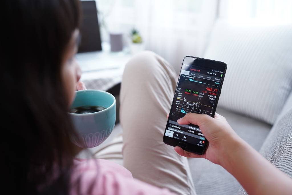 Woman invest online stocks trading on mobile platform app (Wera Rodsawang/Getty Images)