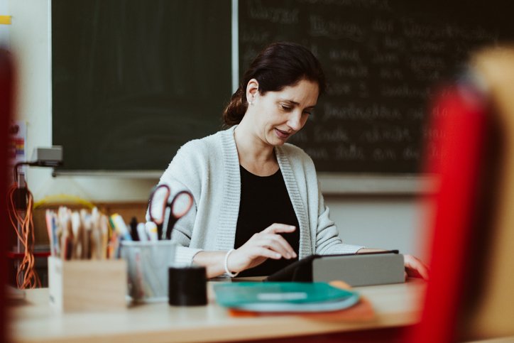 Female teacher sitting at a desk and working with a tablet computer (Getty/Getty Images)