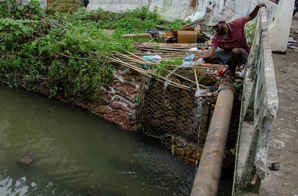 Homem coleta água em cano no Recreio dos Bandeirantes, Rio de Janeiro: startups buscam resolver problema de acesso à água (TERCIO TEIXEIRA/Getty Images)