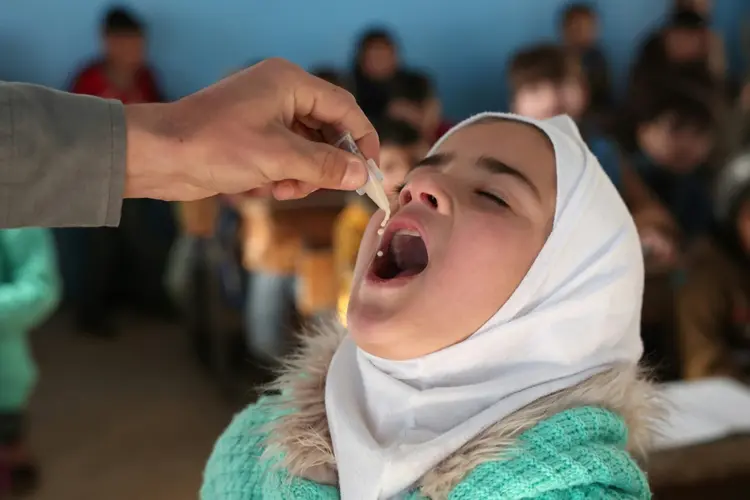 Um médico aplica a vacina contra cólera em uma criança durante uma campanha de vacinação na cidade de Maaret Misrin, na parte norte controlada pelos rebeldes da província de Idlib (AFP/AFP)