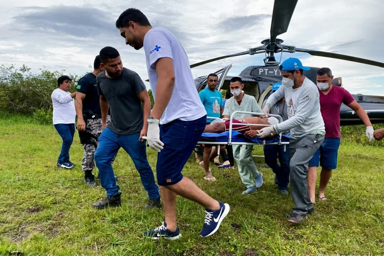 Trabalhadores sanitários transportam um indígena yanomami en Alto Alegre, no estado de Roraima (AFP/AFP Photo)