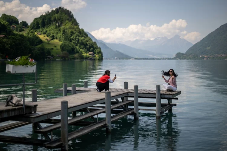 Turistas no famoso cais de uma série sul-coreana da Netflix no povoado de Iseltwald, às margens do lago Brienz, nos Alpes suíços. (AFP/AFP)