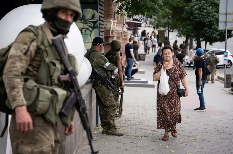 Moradores passam por combatentes do grupo paramilitar Wagner em Rostov-on-Don, em 25 de junho de 2023 (AFP/AFP Photo)