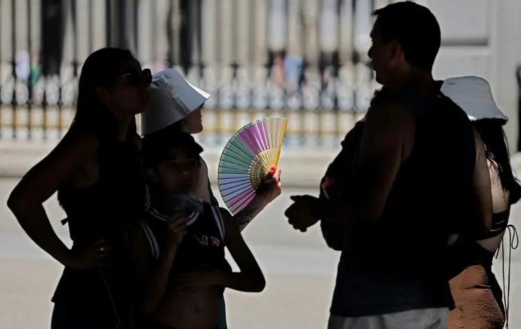 Turistas se abanam na sombra para se proteger do calor enquanto esperam para visitar o Palácio Real, em 26 de junho de 2023, em Madri, durante onda de calor que afeta grande parte da Espanha (AFP/AFP)