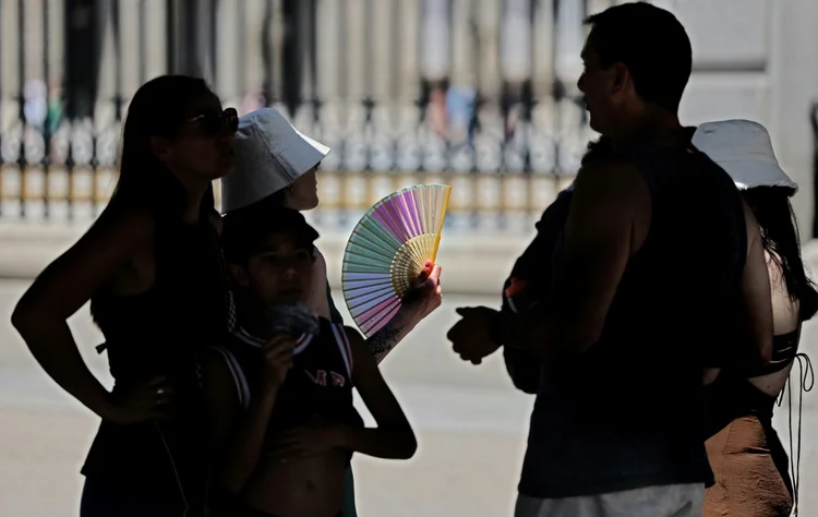 Turistas se abanam na sombra para se proteger do calor enquanto esperam para visitar o Palácio Real, em 26 de junho de 2023, em Madri, durante onda de calor que afeta grande parte da Espanha (AFP/AFP)